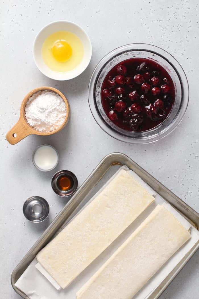 Ingredients for cherry turnovers arranged on a white countertop