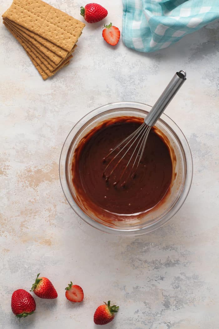 Whisk stirring chocolate ganache in a small glass bowl