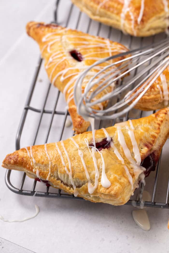 Whisk drizzling glaze over the top of cherry turnovers
