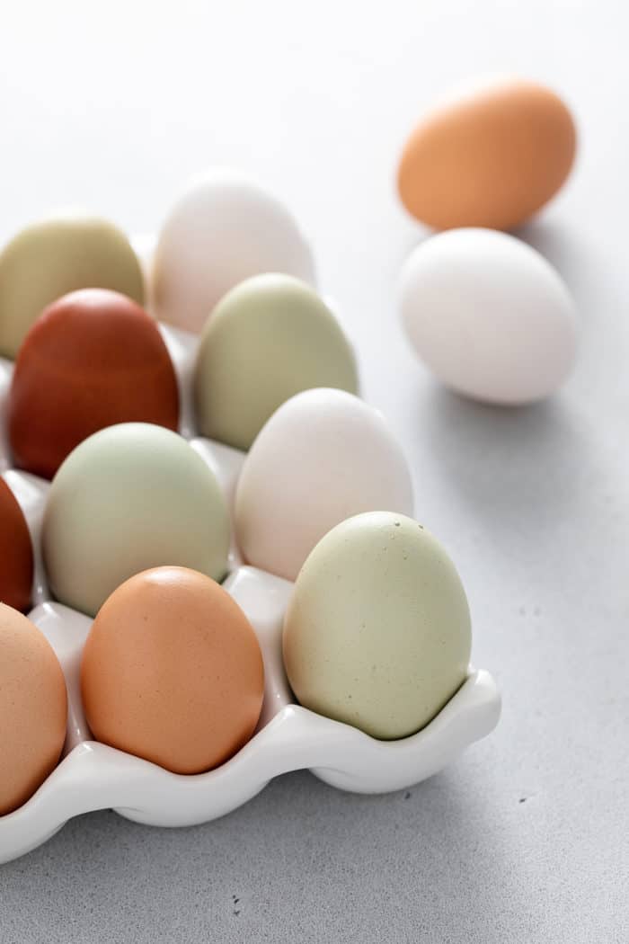 Various colored eggs in an egg holder set on a light gray countertop