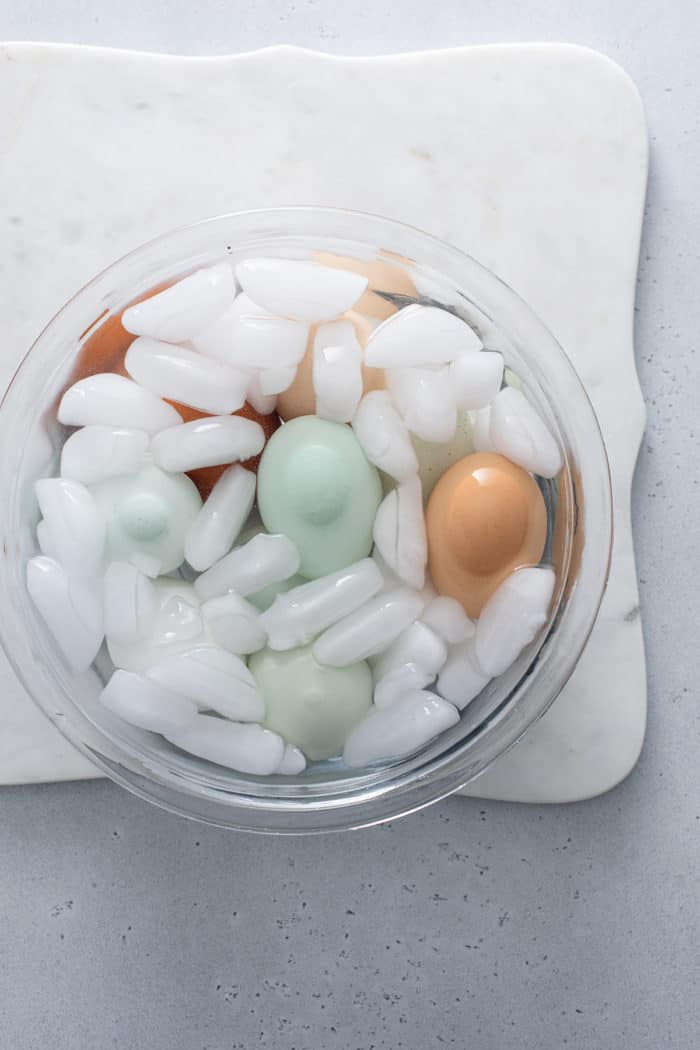 Hard boiled eggs in an ice bath within a glass mixing bowl