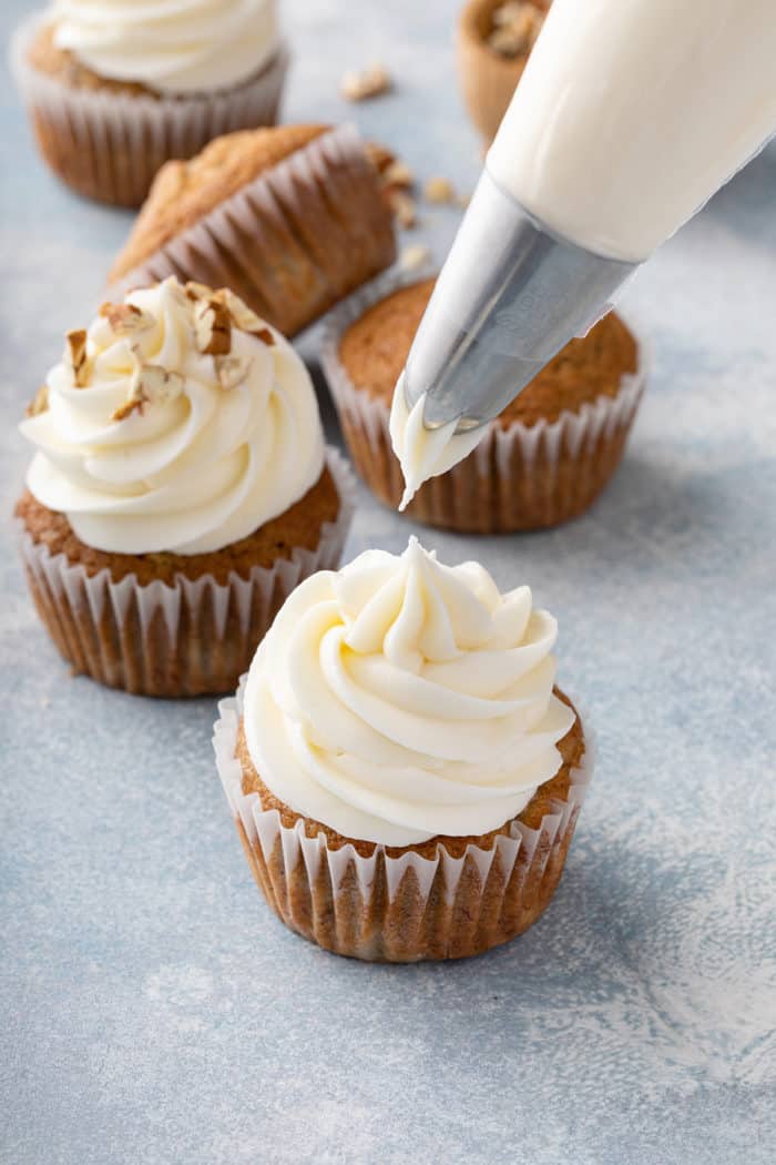 Cream cheese frosting being piped onto a banana cupcake