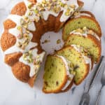 Overhead view of sliced pistachio pudding cake on a marble countertop