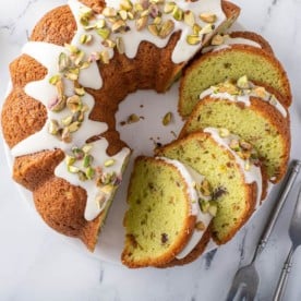 Overhead view of sliced pistachio pudding cake on a marble countertop