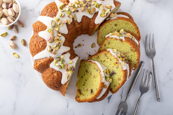 Overhead view of sliced pistachio pudding cake on a marble countertop