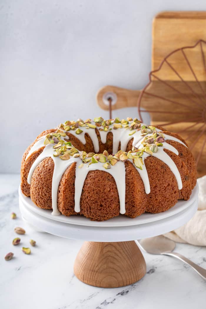 Glazed pistachio pudding cake set on a white cake stand