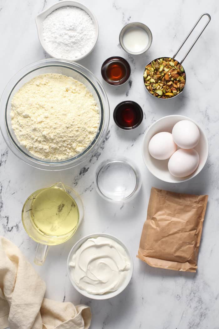 Ingredients for pistachio pudding cake arranged on a marble countertop