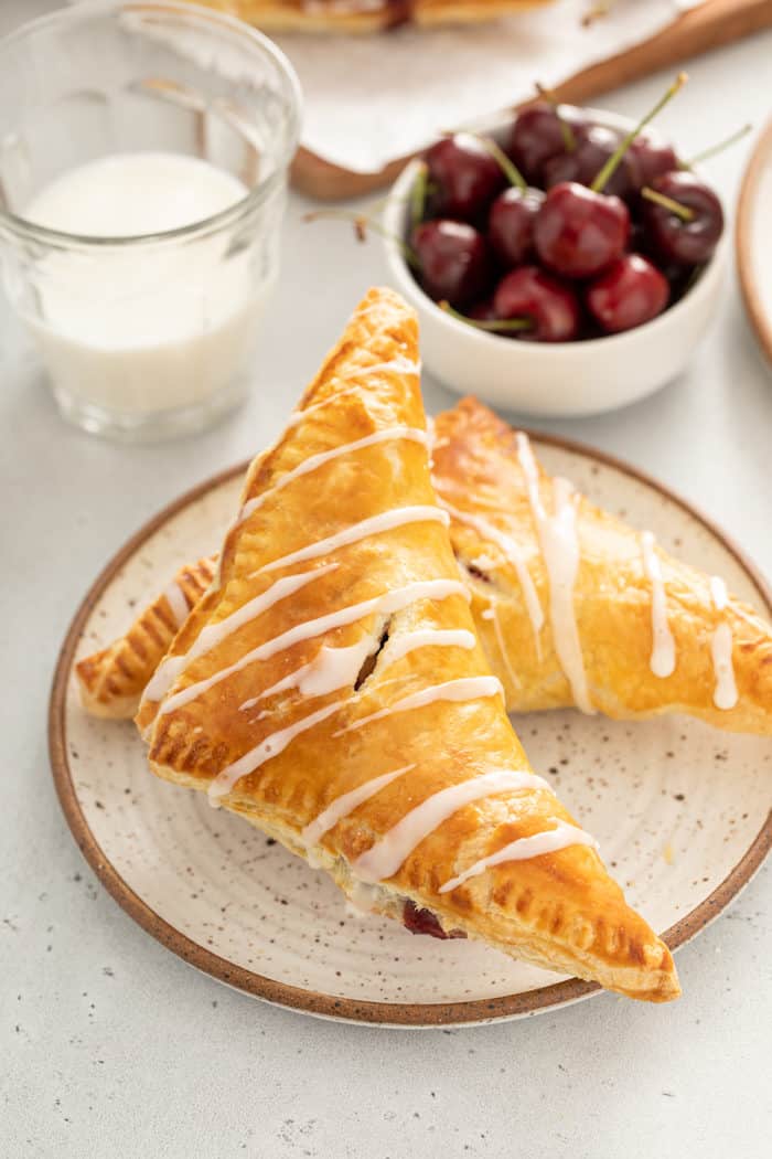 Two glazed cherry turnovers arranged on a light-colored plate