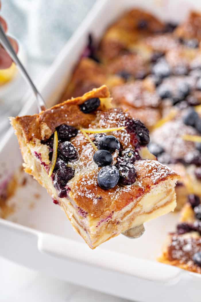 Slice of blueberry bread pudding being lifted out of the baking pan to serve