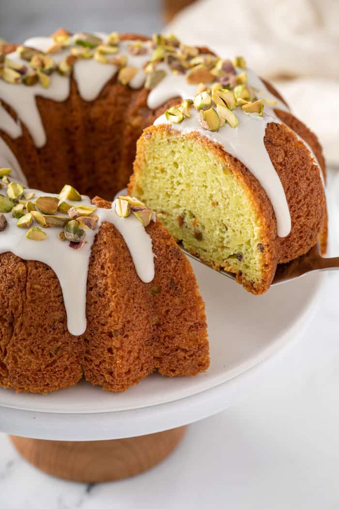 Cake server removing a slice of pistachio pudding bundt cake