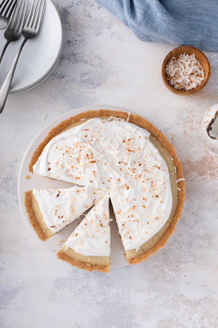 Overhead view of a sliced coconut cream pie, topped with toasted coconut