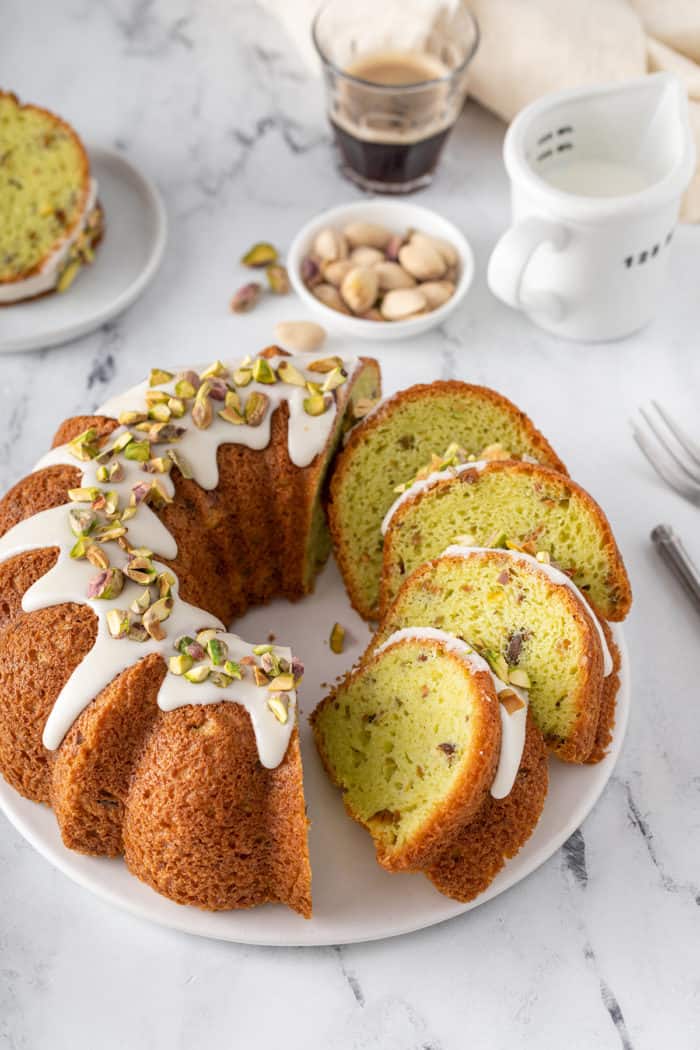 Sliced pistachio pudding cake on a white platter