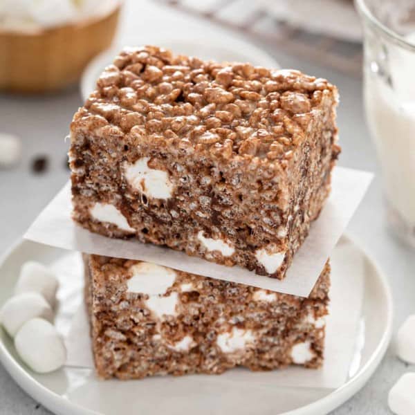 Two chocolate rice krispie treats stacked on a white plate