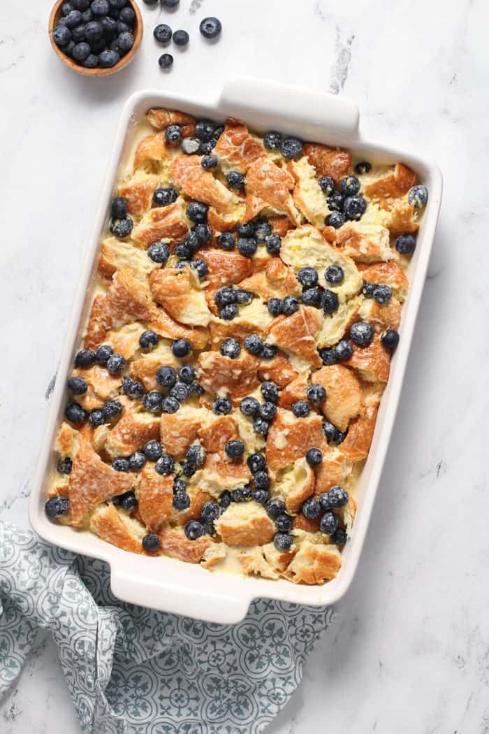 Blueberry bread pudding in a white baking dish, ready to go in the oven