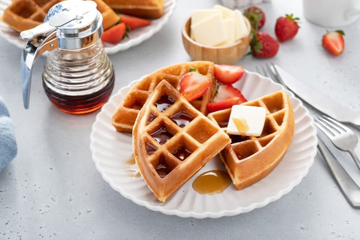 Plated bisquick waffles topped with syrup and butter and fresh strawberries