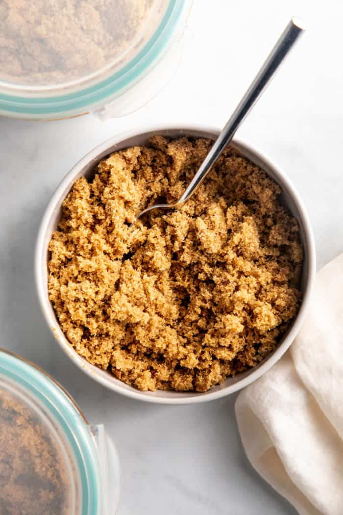 Dark brown sugar substitute being stirred with a spoon in a white bowl