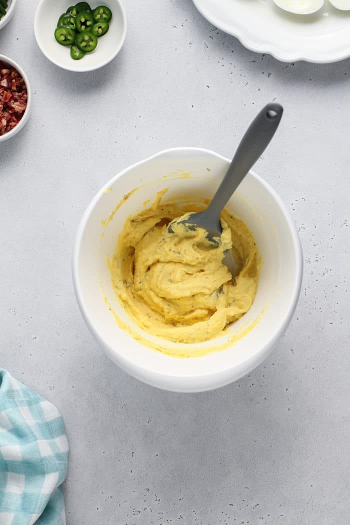 Deviled egg filling in a white mixing bowl, set on a white countertop