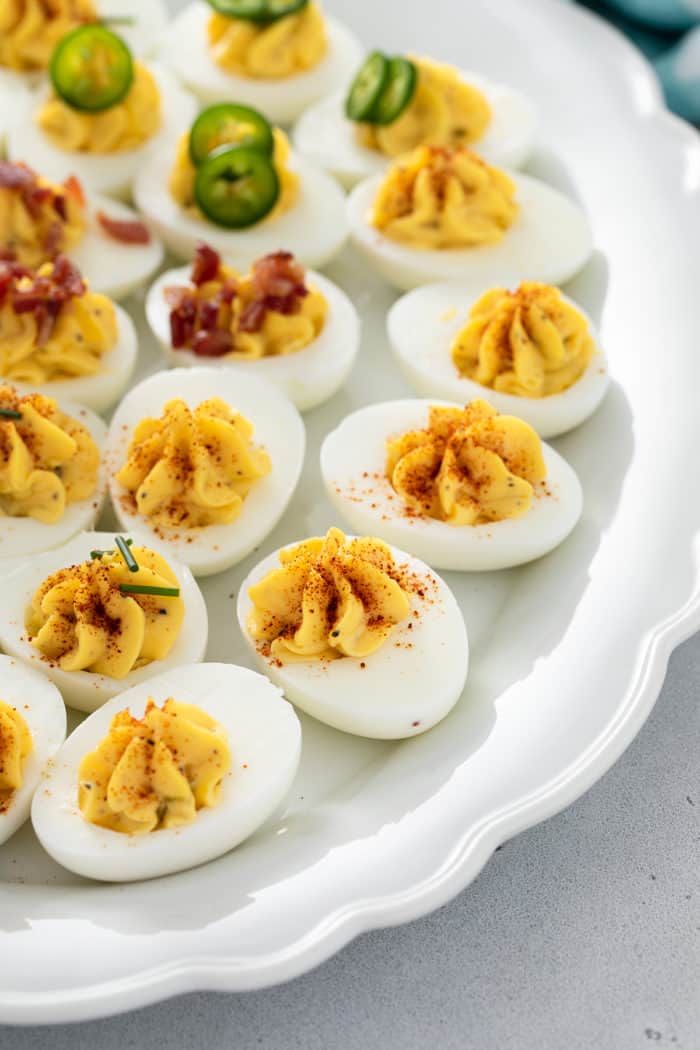 Close up of classic deviled eggs, topped with paprika, on a white platter