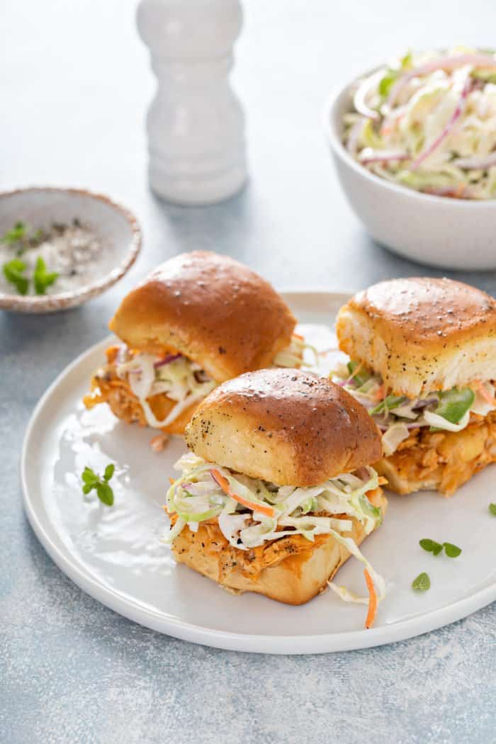 White plate filled with sliders topped with easy coleslaw