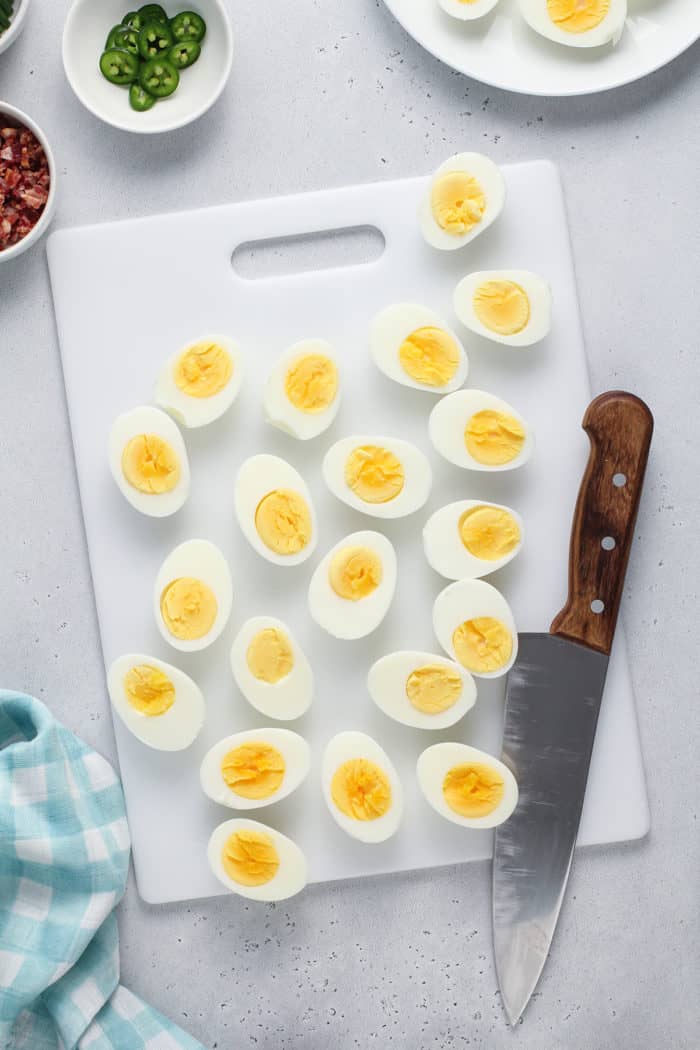 Halved hard boiled eggs on a white cutting board