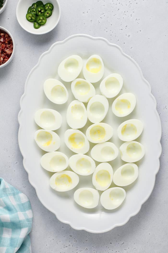 Halved hard boiled egg whites arranged on a white platter