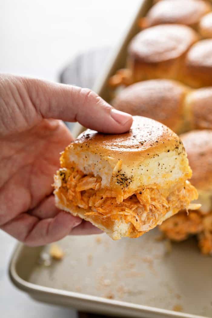 Hand holding a buffalo chicken slider up to the camera