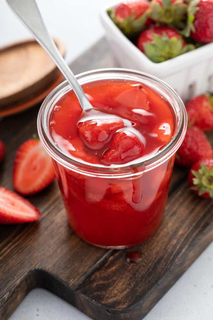 Strawberry sauce in a glass jar with a spoon set in the jar