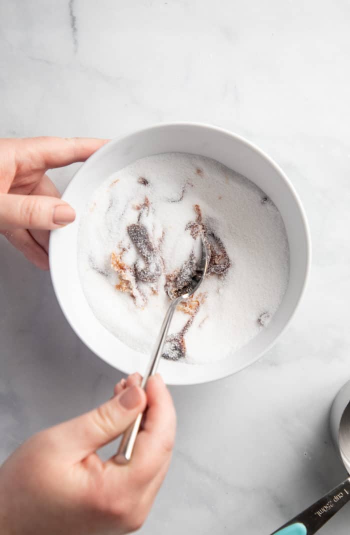 Spoon stirring together molasses and sugar in a white bowl