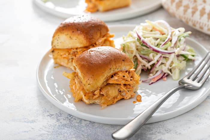 Plate of two buffalo chicken sliders next to coleslaw