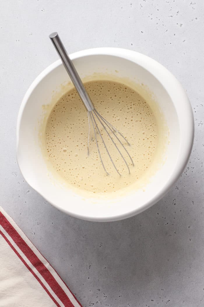 Pancake batter being whisked together in a white mixing bowl