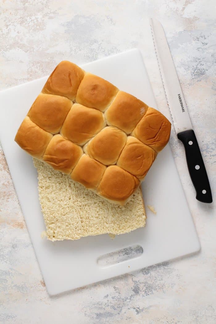 Hawaiian rolls sliced in half on a white cutting board