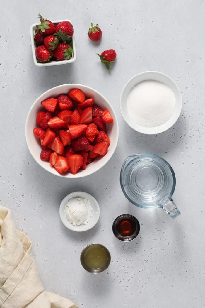 Ingredients for strawberry sauce arranged on a gray countertop