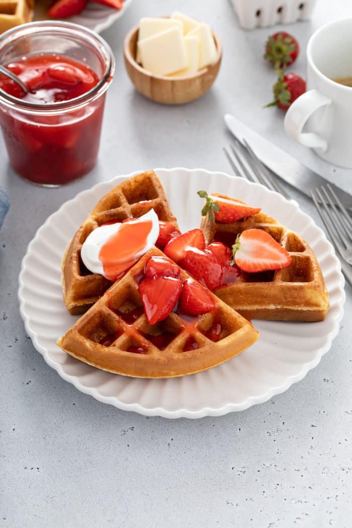 Waffles topped with strawberry sauce on a white plate