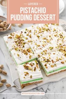 Sliced pistachio pudding dessert on a marble countertop with a piece being removed from the corner.