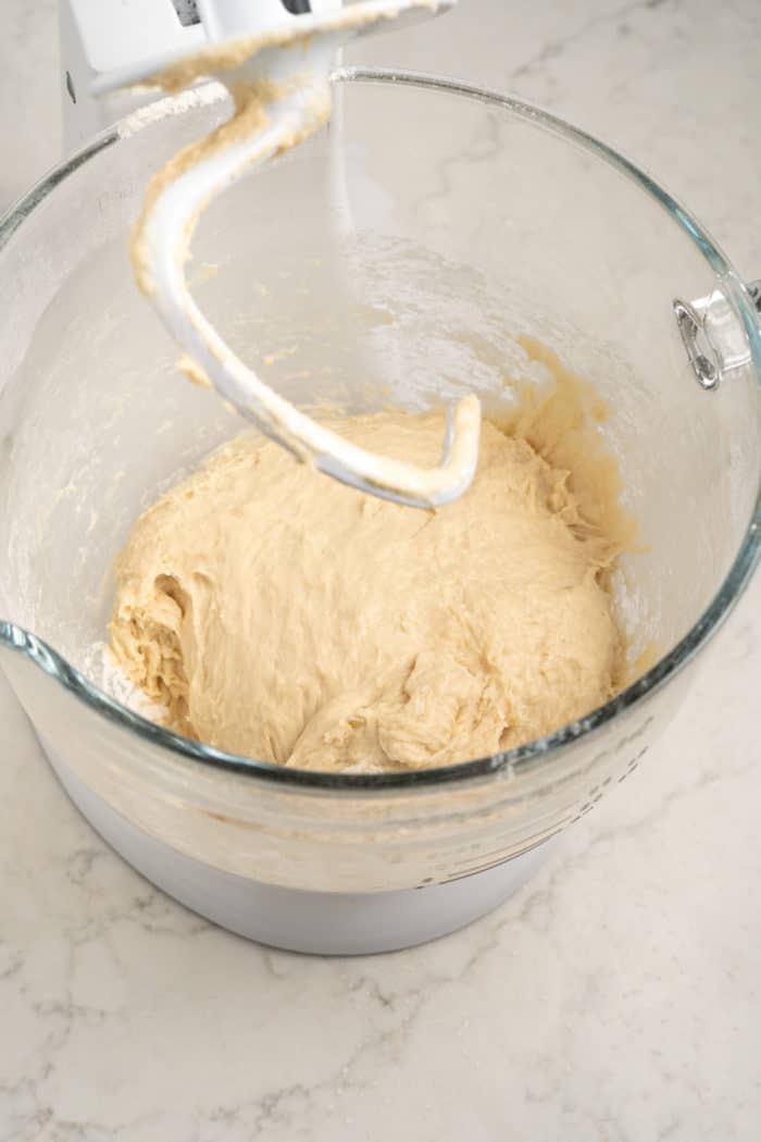 Mixed cinnamon roll dough in a stand mixer bowl fitted with the dough hook