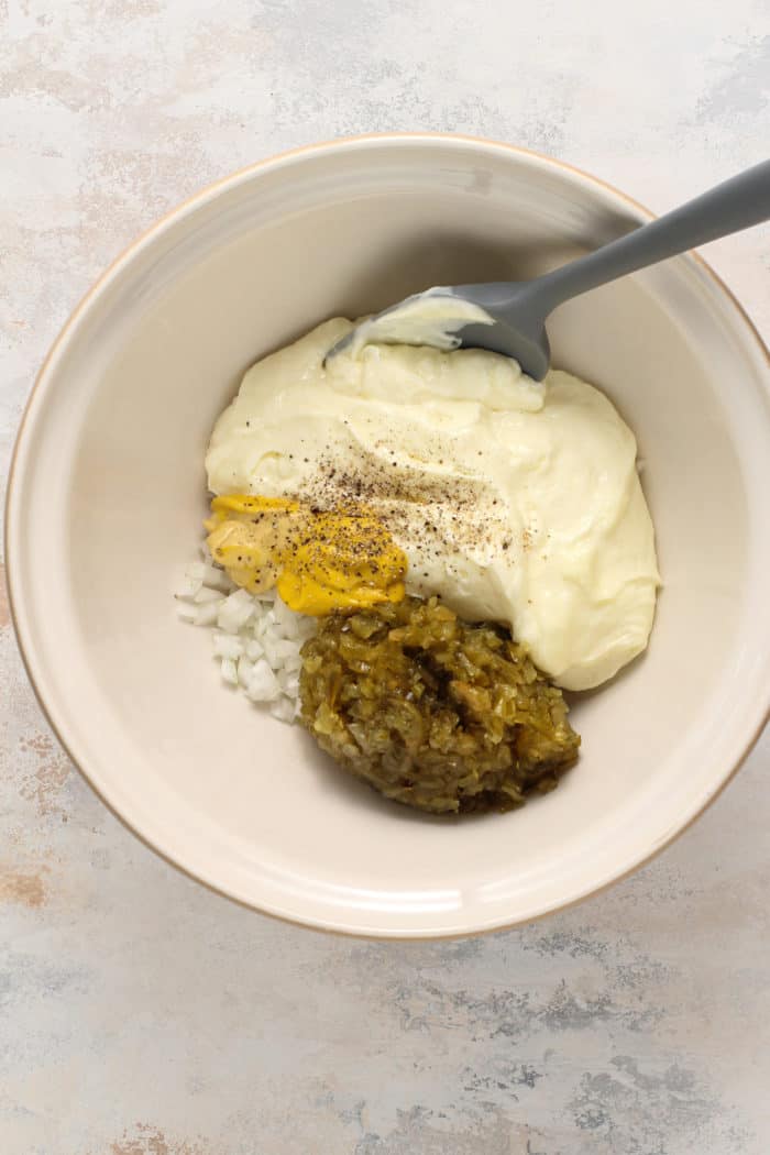 Ingredients for potato salad dressing in a large ceramic mixing bowl.