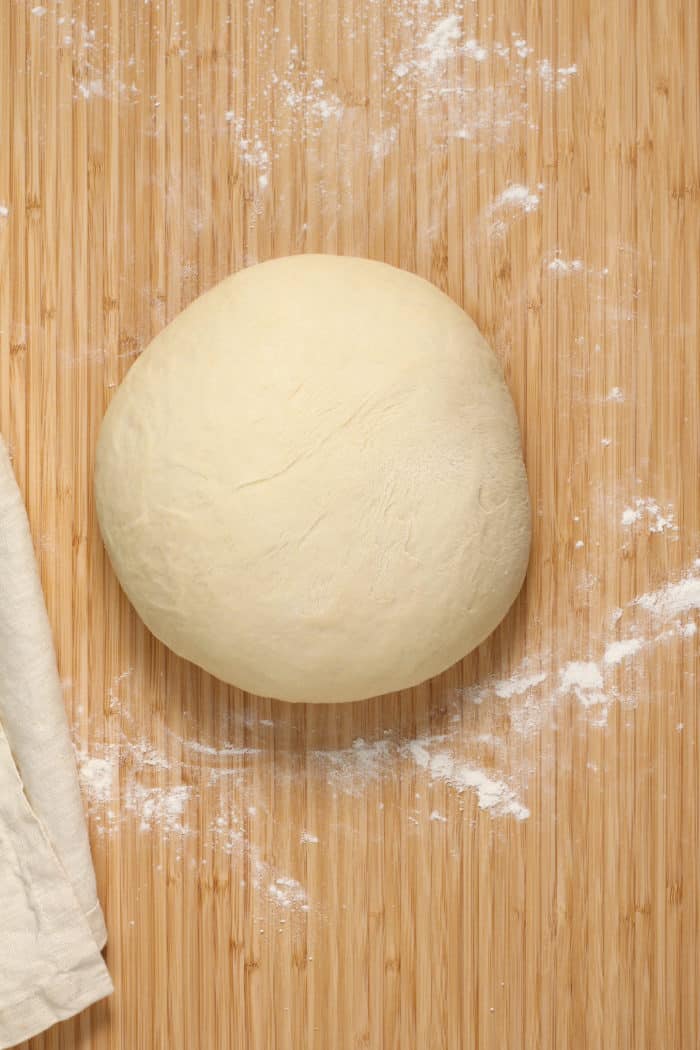 Kneaded dough for overnight cinnamon rolls set on a floured wooden surface