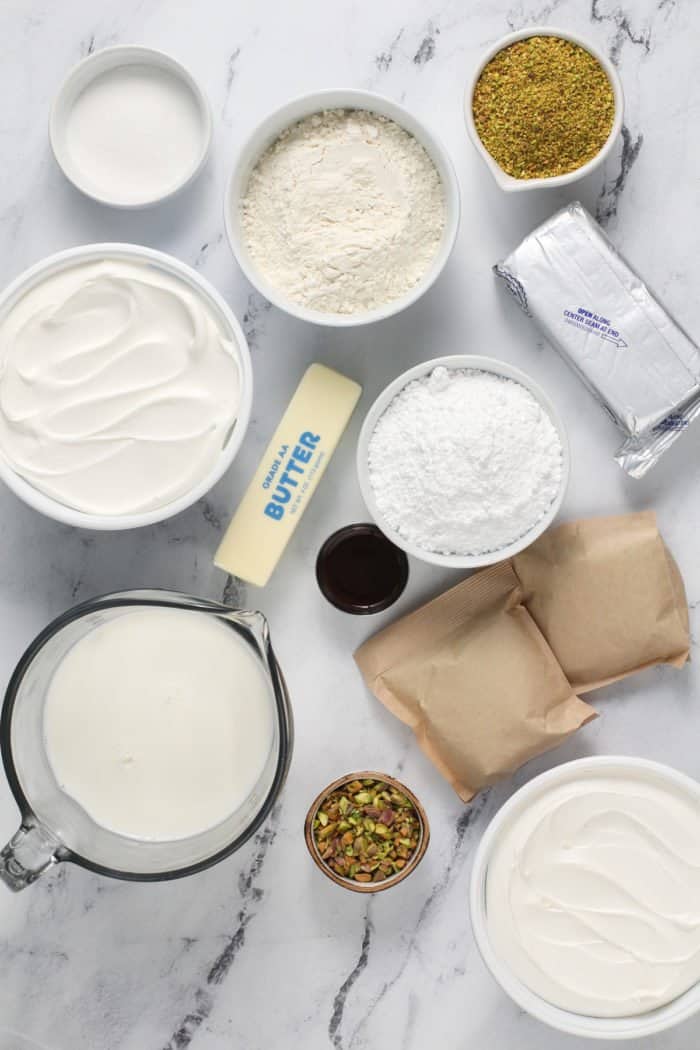 Ingredients for pistachio pudding dessert arranged on a marble countertop.