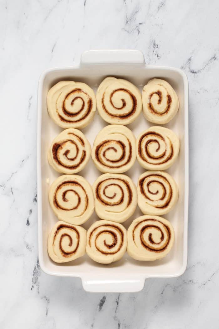 Sliced cinnamon rolls in a white pan, ready to rise