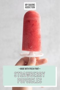 Hand holding a strawberry popsicle in front of a white wall. Text overlay includes recipe name.