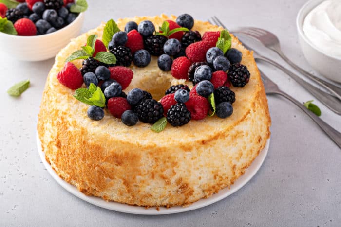 Pineapple angel food cake on a cake plate, topped with fresh berries.
