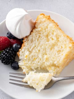 Fork taking a bite from a slice of pineapple angel food cake.