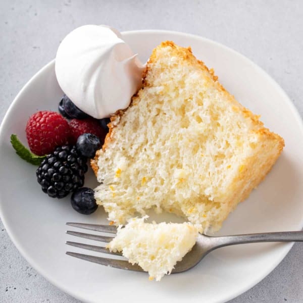 Fork taking a bite from a slice of pineapple angel food cake.