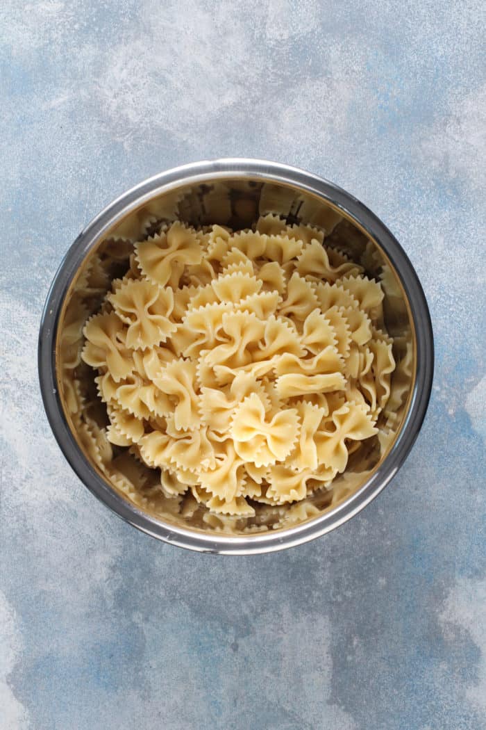 Cooked bowtie pasta in a metal mixing bowl.