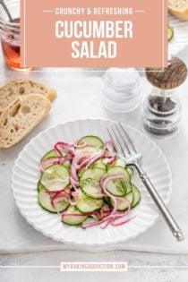 Cucumber salad on a white plate set next to slices of bread. Text overlay includes recipe name.
