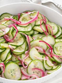 Large white serving bowl filled with cucumber salad.