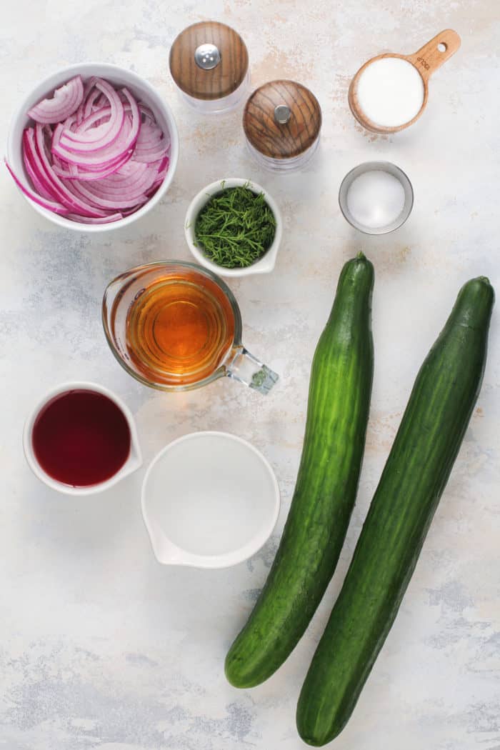 Cucumber salad ingredients arranged on a light-colored countertop.