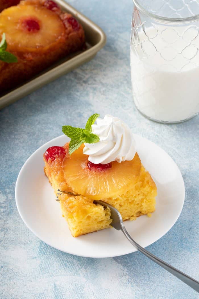 Fork taking a bite of pineapple upside down cake.