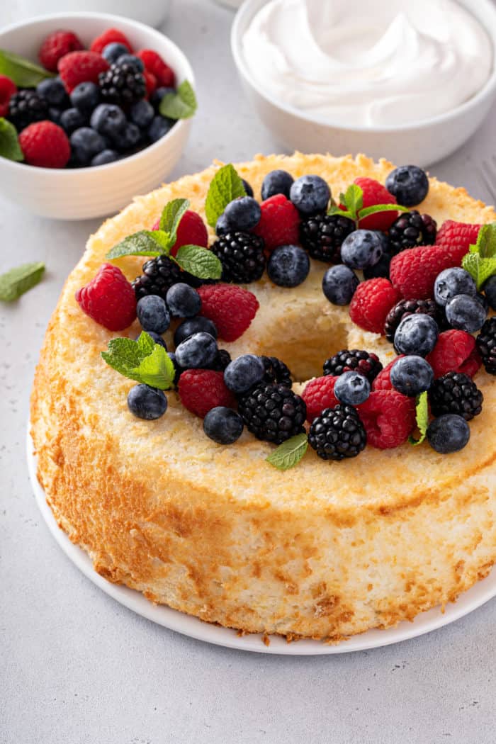 Angel food cake topped with fresh berries and sprigs of mint.