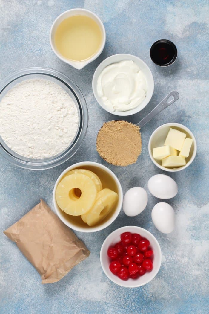 Easy pineapple upside-down cake ingredients arranged on a light blue countertop.